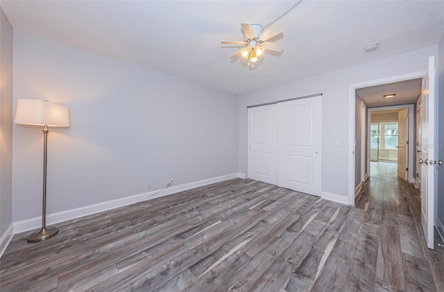 unfurnished bedroom featuring wood finished floors, baseboards, ceiling fan, a closet, and a textured ceiling