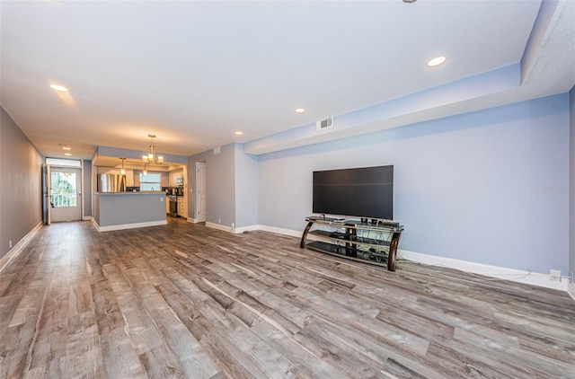 unfurnished living room featuring visible vents, a notable chandelier, wood finished floors, recessed lighting, and baseboards