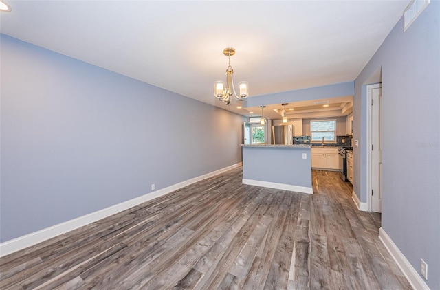 interior space with dark wood-type flooring, appliances with stainless steel finishes, baseboards, a chandelier, and hanging light fixtures