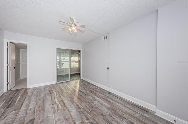 unfurnished bedroom featuring wood finished floors, visible vents, baseboards, ceiling fan, and a textured ceiling