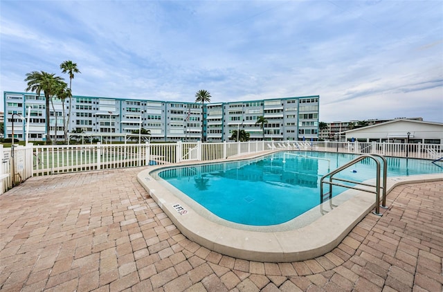 community pool with a patio area and fence