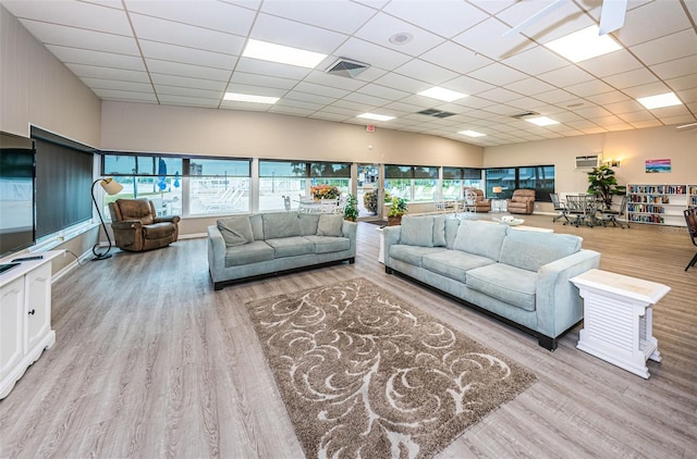 living area with a drop ceiling, visible vents, and wood finished floors