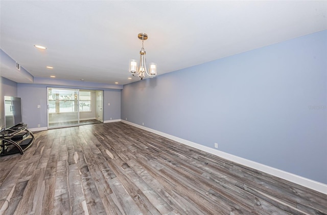 empty room with wood finished floors, baseboards, visible vents, an inviting chandelier, and recessed lighting