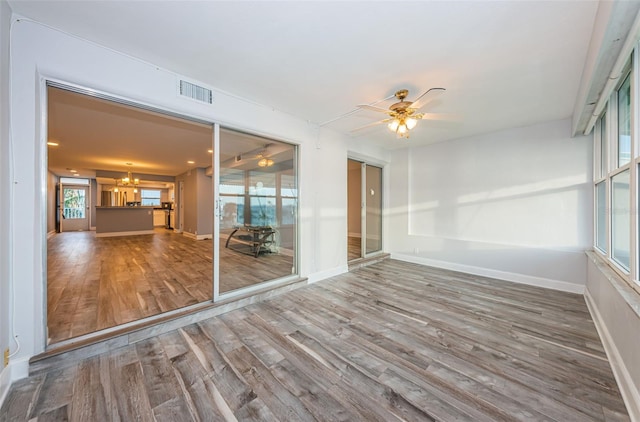 unfurnished sunroom with visible vents and ceiling fan with notable chandelier