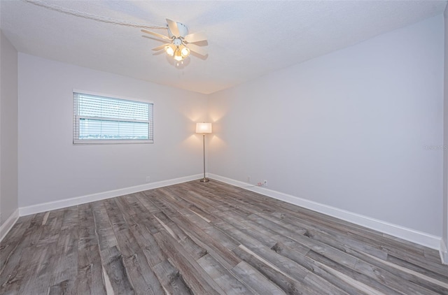 spare room featuring baseboards, wood finished floors, and a ceiling fan