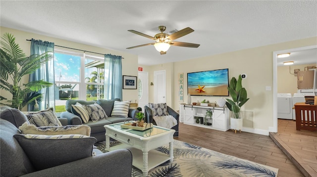 living room with ceiling fan, washing machine and dryer, light hardwood / wood-style floors, and a textured ceiling