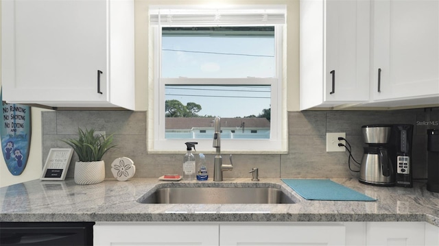 kitchen with white cabinets, tasteful backsplash, light stone countertops, and sink