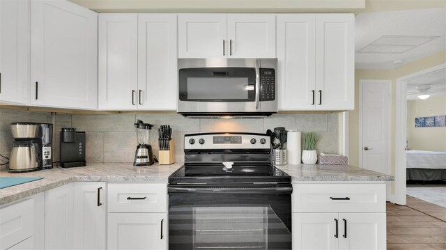 kitchen with ceiling fan, white cabinetry, backsplash, and range with electric cooktop