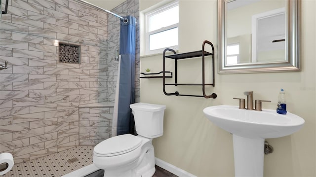 bathroom featuring toilet, a tile shower, and a wealth of natural light