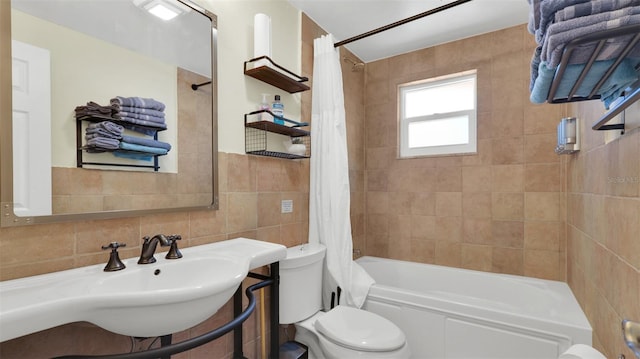 bathroom with tile walls, toilet, and shower / bath combo with shower curtain