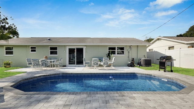 back of house with central air condition unit, a patio area, and a fenced in pool