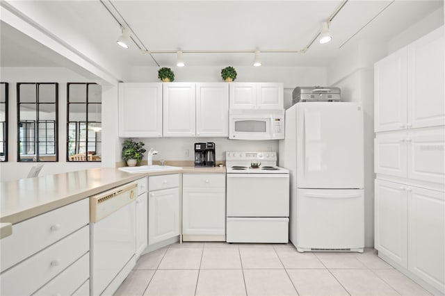 kitchen featuring light tile flooring, rail lighting, white appliances, white cabinetry, and sink