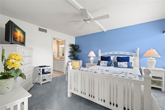 bedroom featuring a textured ceiling, dark carpet, ceiling fan, and ensuite bathroom