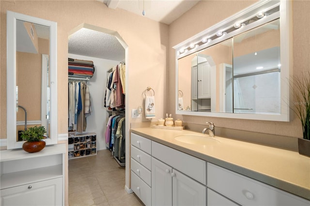 bathroom with a textured ceiling, tile floors, and large vanity