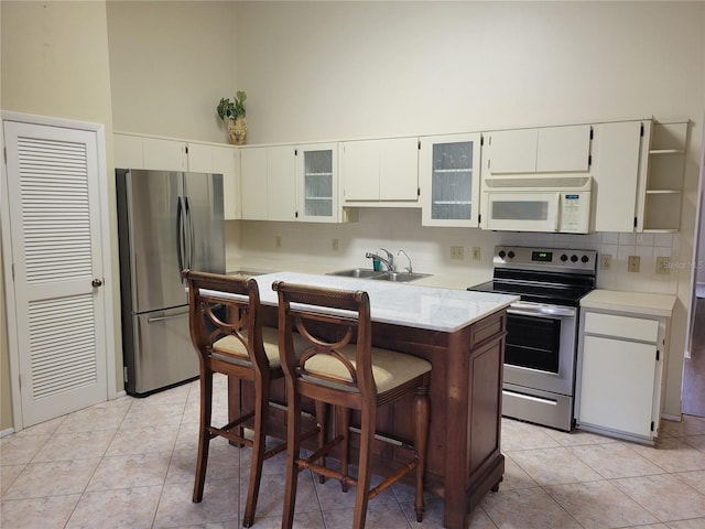 kitchen with light tile floors, a high ceiling, appliances with stainless steel finishes, and sink