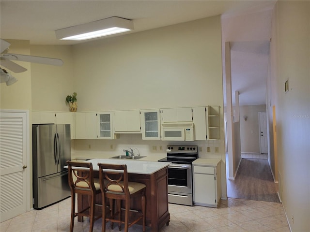 kitchen with ceiling fan, a breakfast bar, light hardwood / wood-style floors, sink, and stainless steel appliances