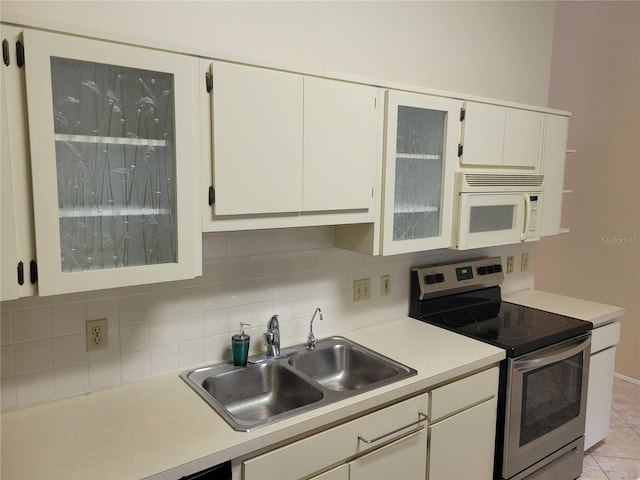 kitchen with stainless steel range with electric cooktop, sink, light tile floors, white cabinets, and backsplash