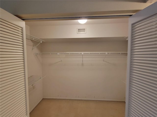 walk in closet with light colored carpet