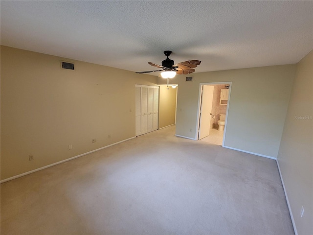 unfurnished bedroom with light colored carpet, connected bathroom, a closet, and ceiling fan