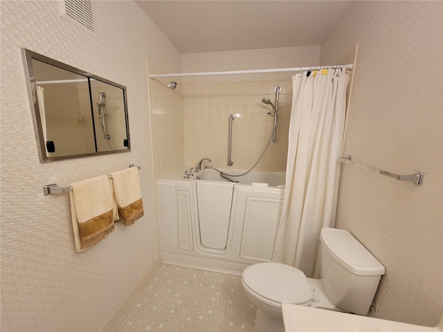 bathroom with tile flooring, washer / clothes dryer, and toilet