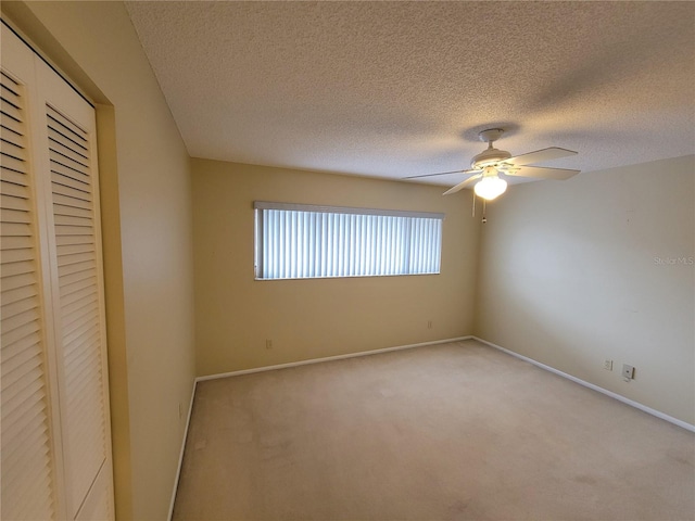 unfurnished bedroom with a closet, a textured ceiling, ceiling fan, and light colored carpet