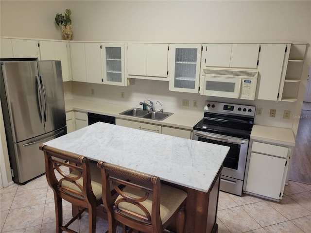 kitchen with sink, a kitchen breakfast bar, appliances with stainless steel finishes, light tile flooring, and tasteful backsplash