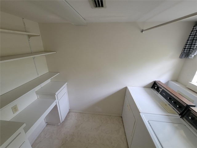 laundry area featuring cabinets, separate washer and dryer, and light tile floors