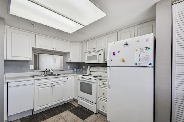 kitchen featuring white appliances, white cabinetry, dark tile flooring, and sink