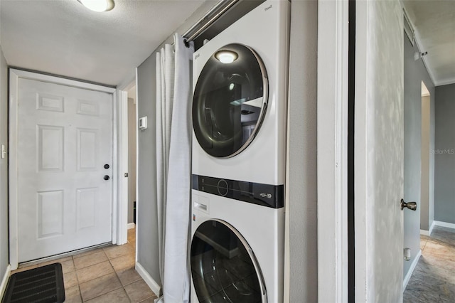 laundry room featuring light tile floors, a textured ceiling, and stacked washer / drying machine