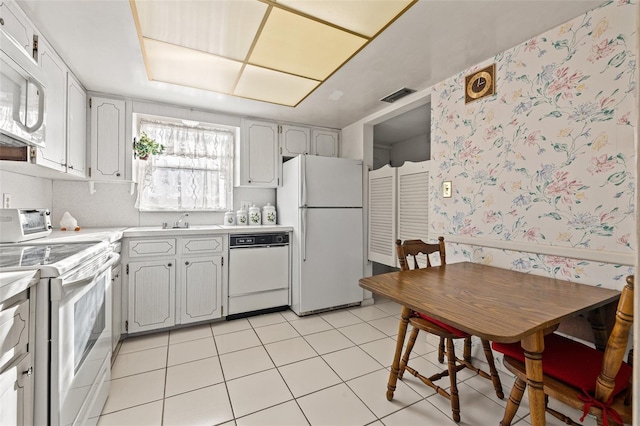 kitchen with white cabinetry, white appliances, sink, and light tile patterned floors