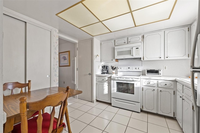 kitchen with white cabinetry, white appliances, and light tile patterned floors