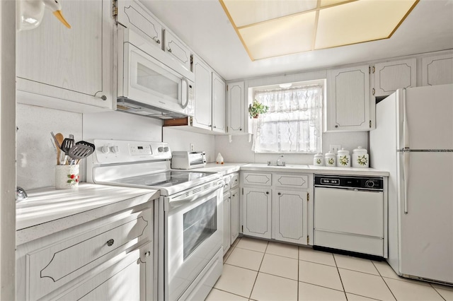 kitchen featuring white cabinetry, white appliances, sink, and light tile patterned floors