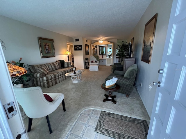 carpeted living room featuring ceiling fan and a textured ceiling