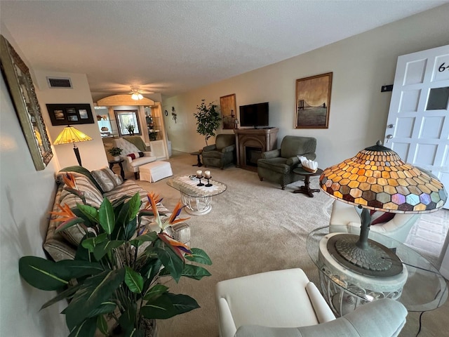 carpeted living room featuring ceiling fan, a fireplace, and a textured ceiling