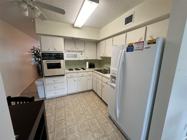 kitchen with ceiling fan, white cabinets, sink, white appliances, and a textured ceiling