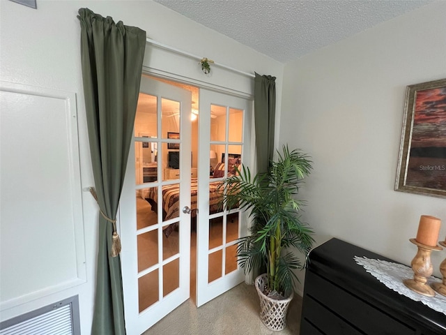 interior space with carpet flooring, a textured ceiling, and french doors