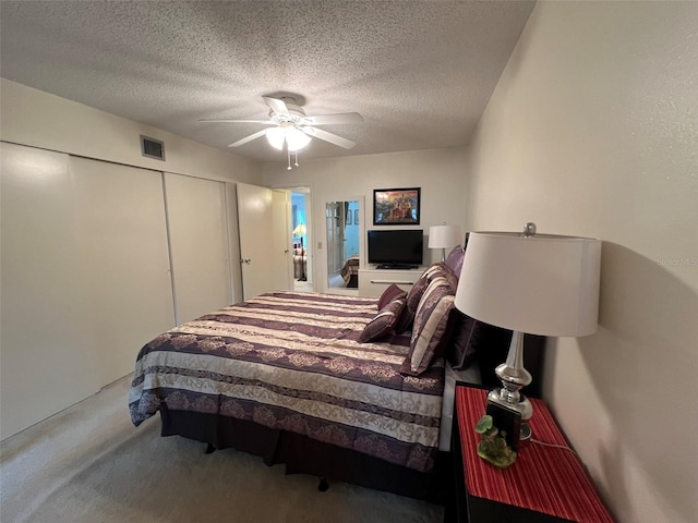 bedroom with a textured ceiling, carpet flooring, ceiling fan, and a closet