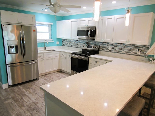 kitchen with backsplash, stainless steel appliances, a kitchen bar, sink, and hanging light fixtures