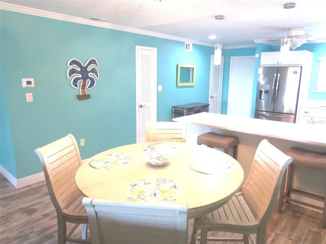 dining room with a textured ceiling, ceiling fan, hardwood / wood-style floors, and ornamental molding