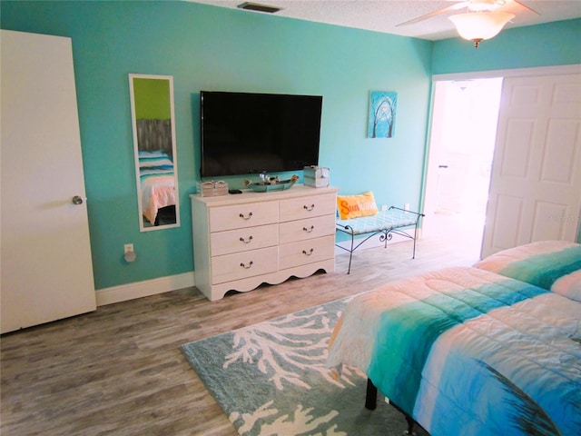 bedroom with ceiling fan, a textured ceiling, and hardwood / wood-style floors