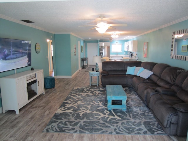 living room featuring ceiling fan, hardwood / wood-style flooring, crown molding, and a textured ceiling