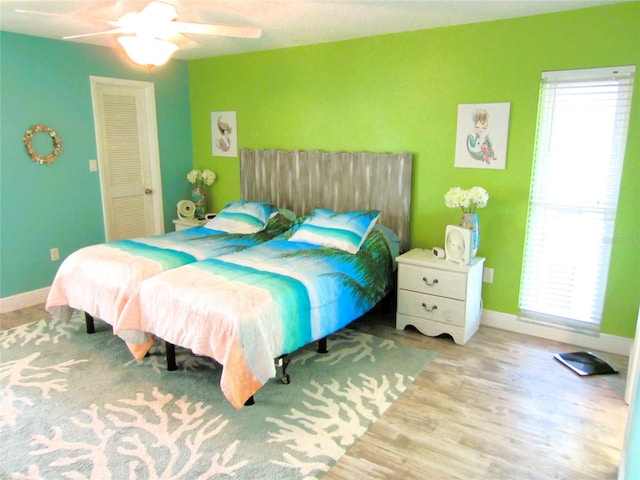 bedroom with ceiling fan, a closet, and light hardwood / wood-style floors