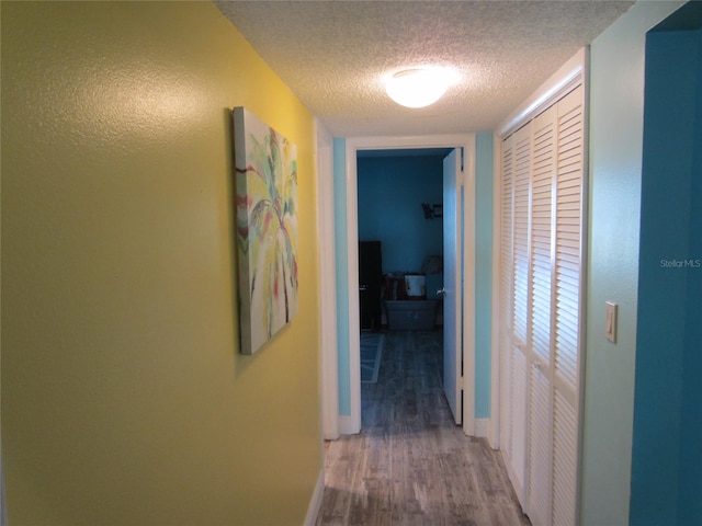 hallway with wood-type flooring and a textured ceiling