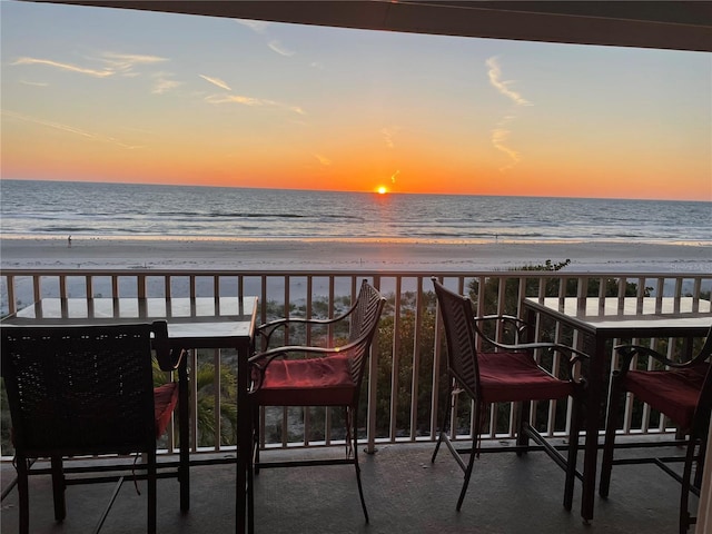 balcony at dusk with a water view and a beach view