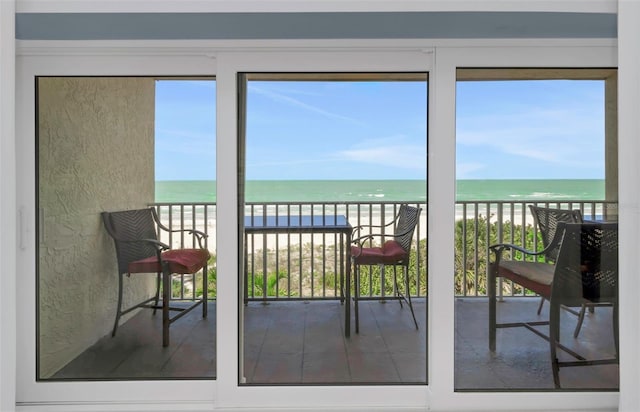 interior space featuring a wealth of natural light, a water view, and a beach view