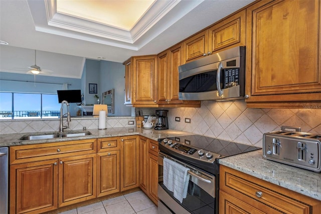 kitchen with light stone countertops, sink, ceiling fan, light tile patterned flooring, and appliances with stainless steel finishes