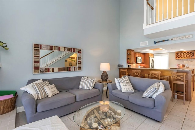 tiled living room with a towering ceiling and indoor bar