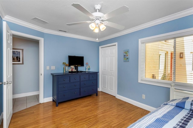 bedroom featuring a closet, ceiling fan, crown molding, and light hardwood / wood-style floors