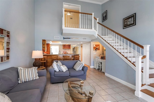 living room with light tile patterned flooring, a towering ceiling, and crown molding