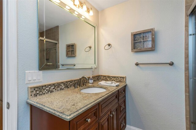 bathroom with vanity, decorative backsplash, and walk in shower